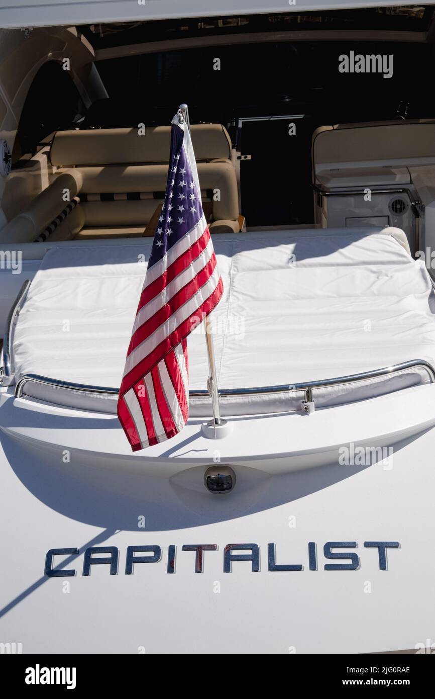 Stern di un lussuoso yacht a motore chiamato capitalista e a poppa lo staff indossava la US Ensign una grande stella e strisce bandiera americana a Newport Beach USA Foto Stock