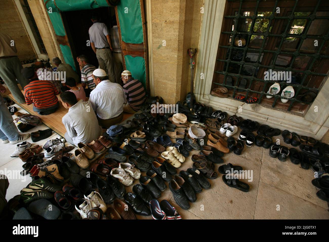 Kırkpınar (olio turco Wrestling). Le scarpe lasciarono accanto all'ingresso durante la preghiera del venerdì (Jumu'ah) nella moschea di Selimiye a Edirne, Turchia. La preghiera congregazionale nella moschea di Selimiye segna l'inizio del torneo annuale di Kırkpınar 648th, il 2 luglio 2009. Il torneo annuale di lotta all'olio turco inizia tradizionalmente con la preghiera del venerdì nella moschea di Selimiye progettata dall'architetto imperiale ottomano Mimar Sinan e costruita tra il 1568 e il 1575. Alcune persone pregano all'esterno perché la moschea è già piena. Foto Stock