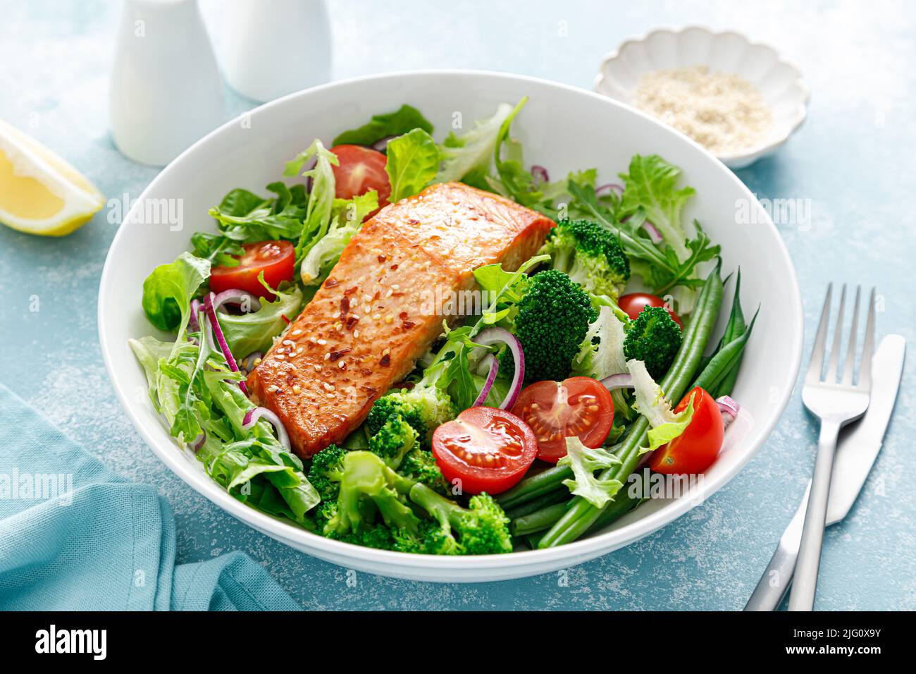 Filetto di pesce al salmone alla griglia e insalata di verdure fresche al pomodoro con lattuga, rucola, broccoli e fagioli verdi. Cibo sano, dieta mediterranea Foto Stock