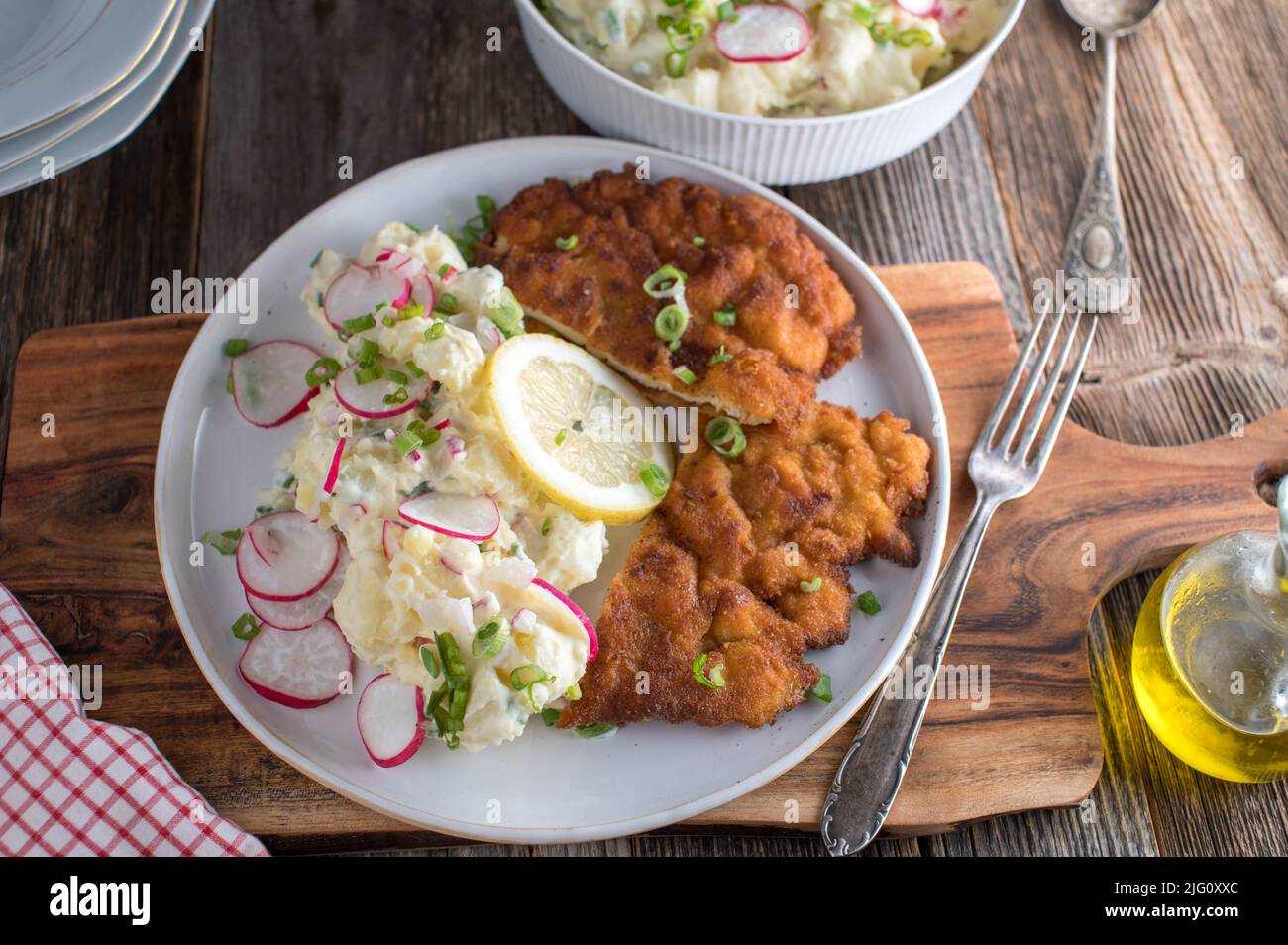 Piatti di conforto tedeschi con una padella fresca fritta di maiale impanato 'Schnitzel'. Servito con insalata di patate fatta in casa su un piatto Foto Stock