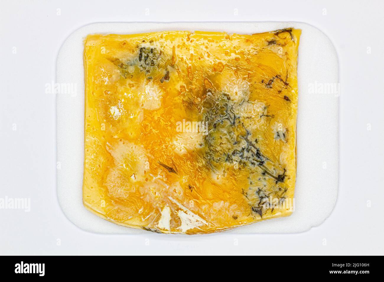Formaggio con muffa. Un grosso pezzo di formaggio affettato con buchi, a lungo stato guastato e ricoperto di muffa. Splendida vista del cibo rovinato. Giallo ammuffito Foto Stock