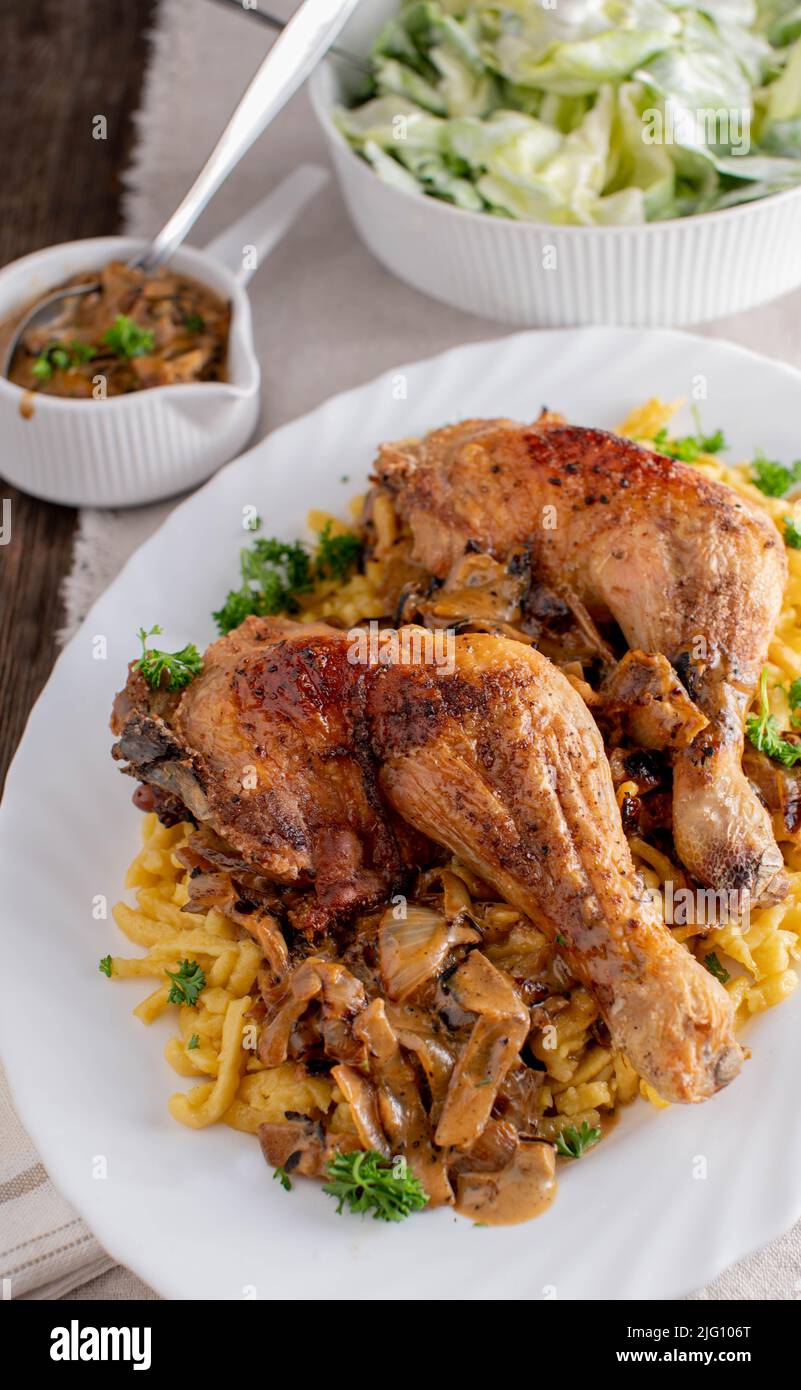 Cosce di pollo con pasta e salsa cremosa di cipolle. Servito con un'insalata verde Foto Stock