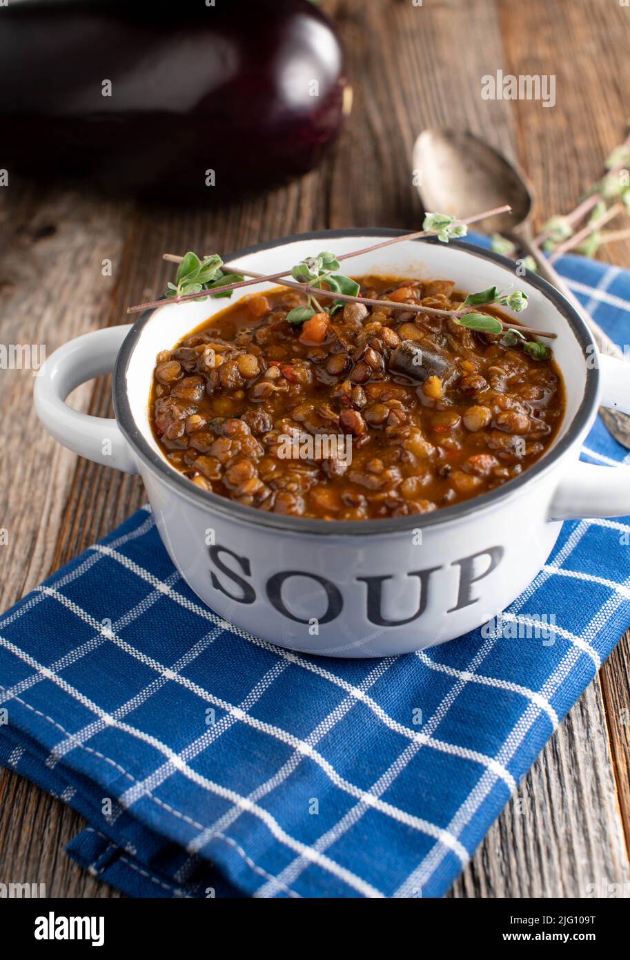 Stufato di lenticchie vegane o vegetariane con verdure e melanzane su tavola di legno. Vista laterale con spazio di copia Foto Stock