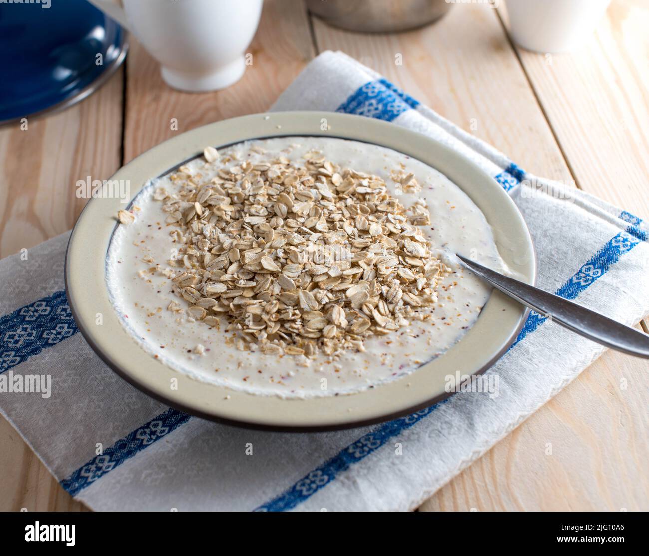 Colazione naturale e salutare con yogurt fresco, avena e mele in purea su un piatto con cucchiaio Foto Stock