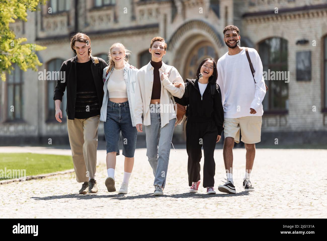 Giovani studenti multietnici che camminano e guardano la macchina fotografica vicino all'università all'aperto Foto Stock