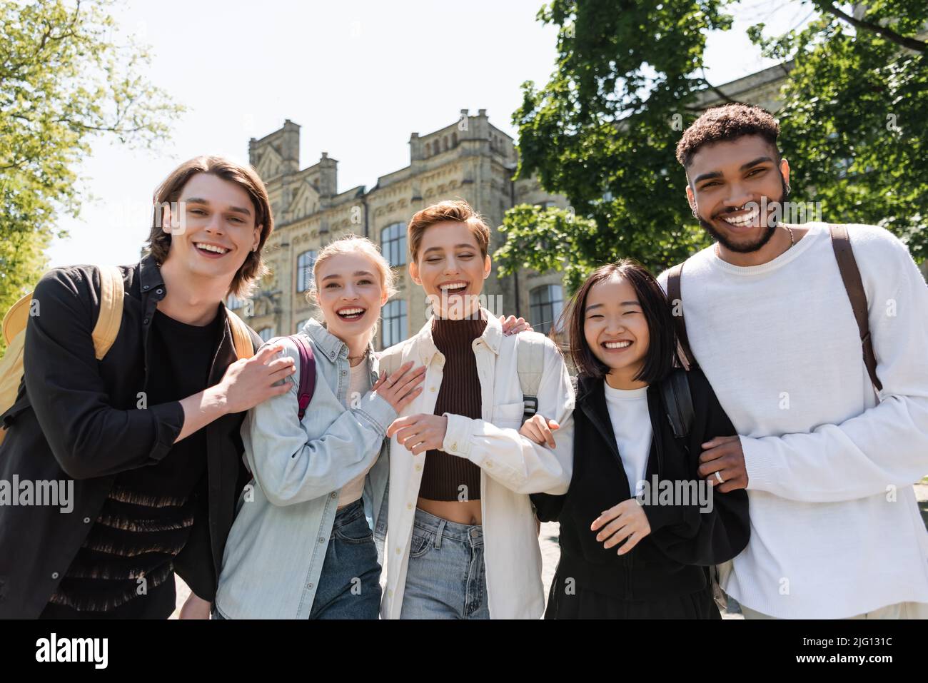 Studenti multietnici positivi che abbraccia e guarda la macchina fotografica all'aperto Foto Stock