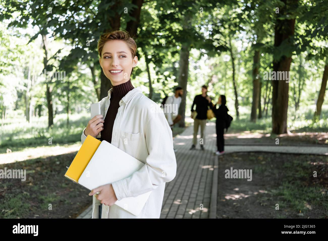 Allegro studente che tiene gadget e notebook nel parco estivo Foto Stock