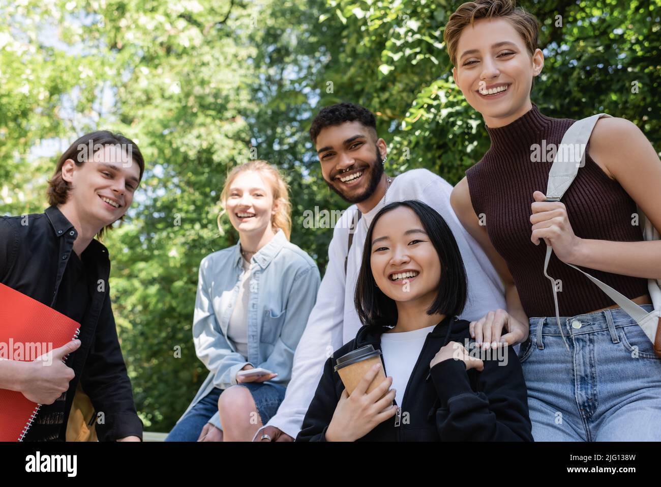 Allegri studenti multiculturali che guardano la macchina fotografica mentre trascorrono del tempo nel parco Foto Stock