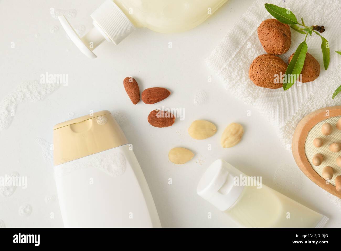 Prodotti per l'igiene personale con estratto di mandorle su tavola bianca con frutta e prodotti da bagno. Vista dall'alto. Composizione orizzontale. Foto Stock