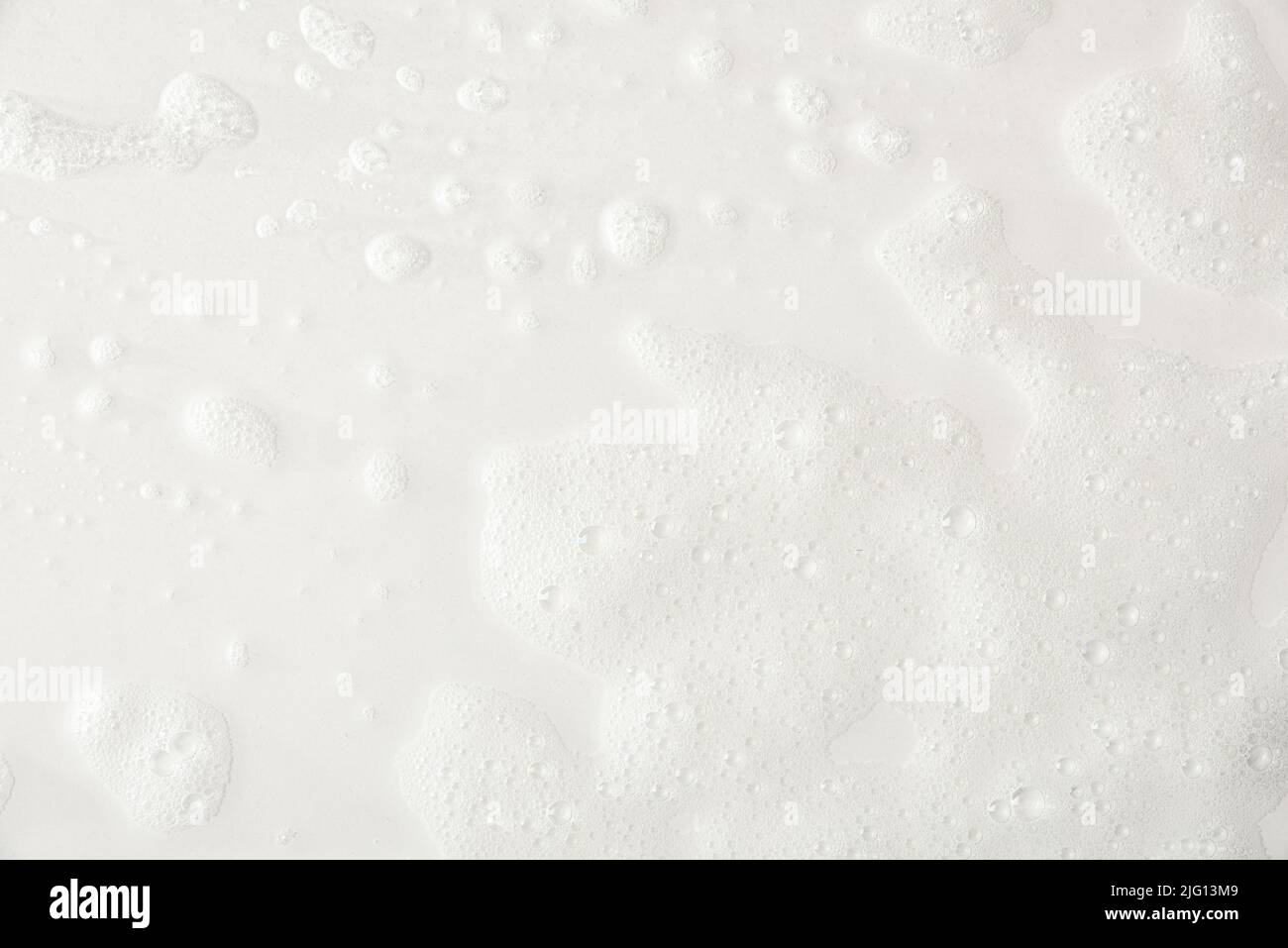 Schiuma su base bianca con tracce di sapone e dettagli di acqua della doccia. Vista dall'alto. Composizione orizzontale. Foto Stock