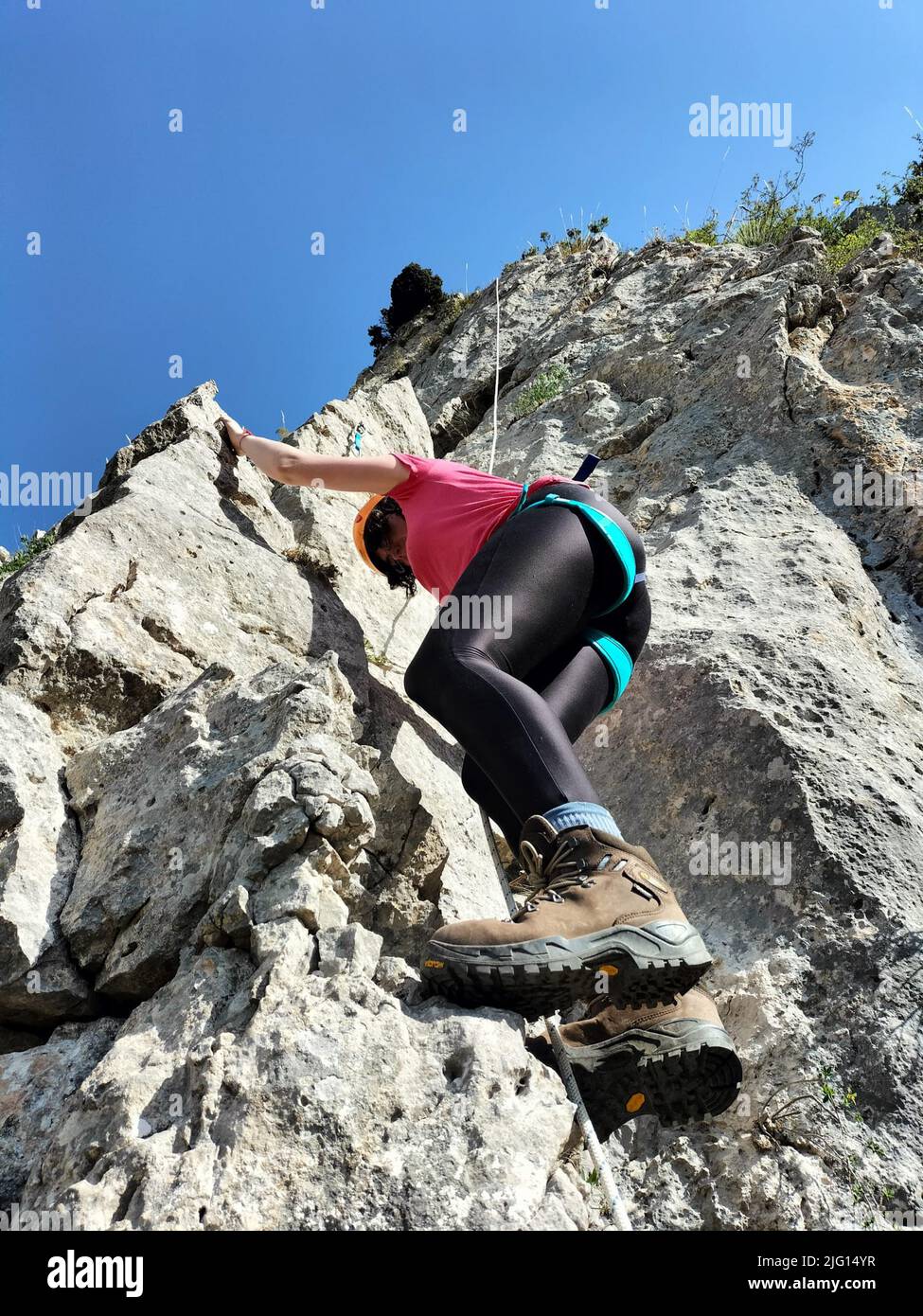 Bella donna che si arrampica su roccia alta al tramonto nebbia in montagna. Concetto di avventura e sport estremi Foto Stock