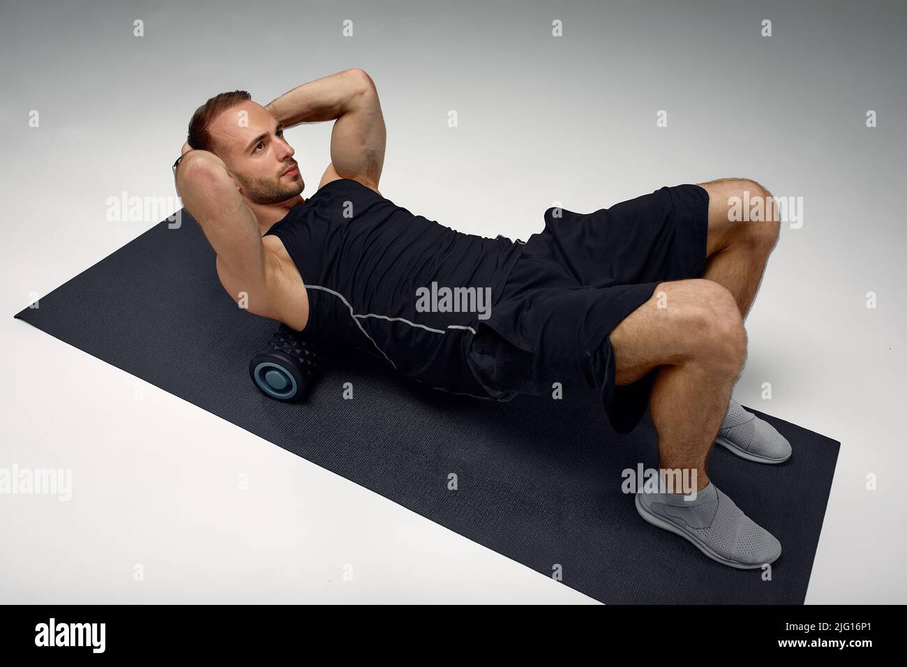 Man Foam Rolling. L'atleta si allunga utilizzando un rullo in schiuma. Foto Stock