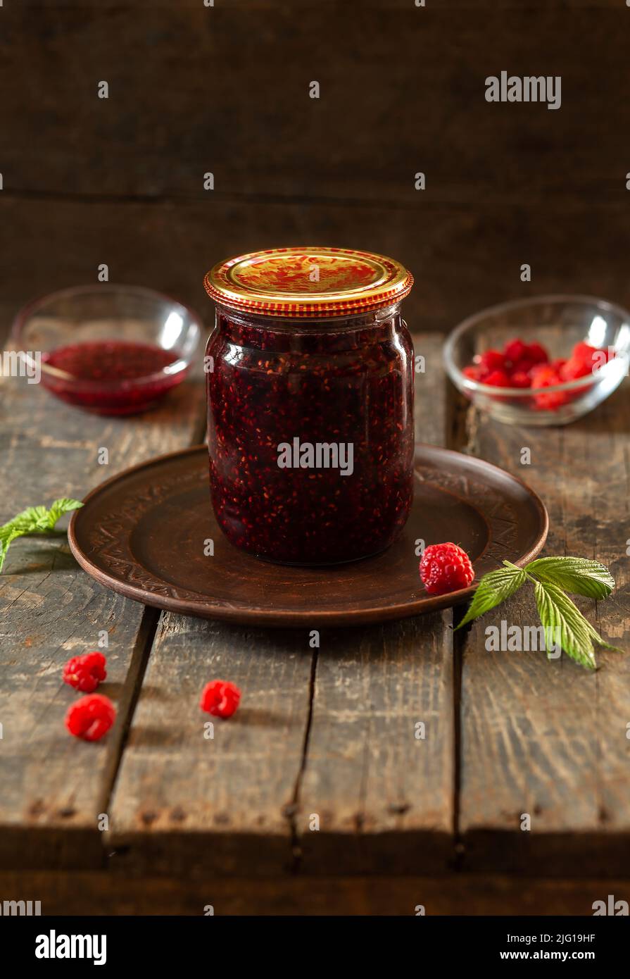 Vaso chiuso di marmellata di lamponi su tavole di legno. Conservazione, cottura, cibo Foto Stock
