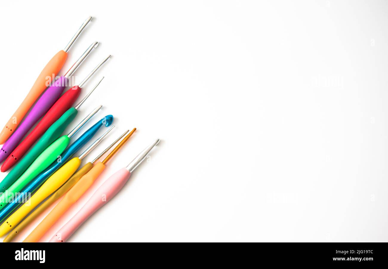 Aghi a crochet luminosi di varie dimensioni isolati su sfondo bianco. Spazio di copia, vista dall'alto. Concetto di idea dell'ago a crochet piatto. Foto Stock