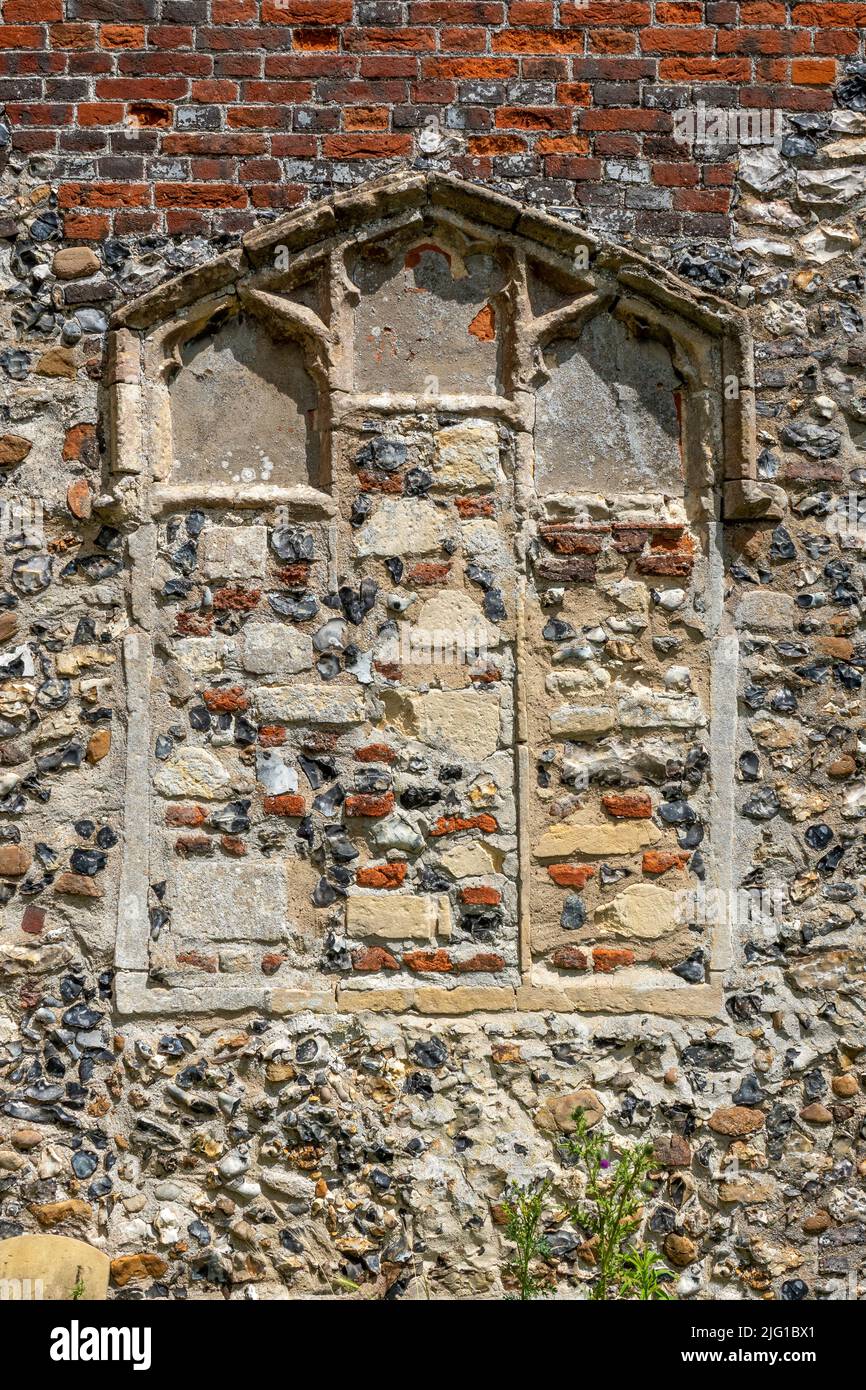 Una cornice bifora in pietra con vetro rimosso e riempito di pietra e pietra selce e mattoni, All Saints Church, Laxfield, Suffolk Foto Stock