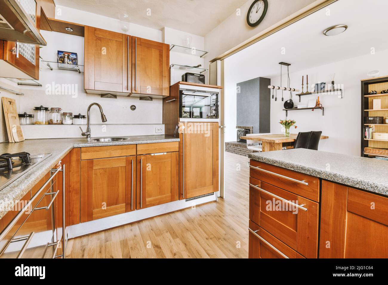 Design interno moderno di una cucina ad angolo con mobili marroni accanto alla zona pranzo in una casa moderna Foto Stock