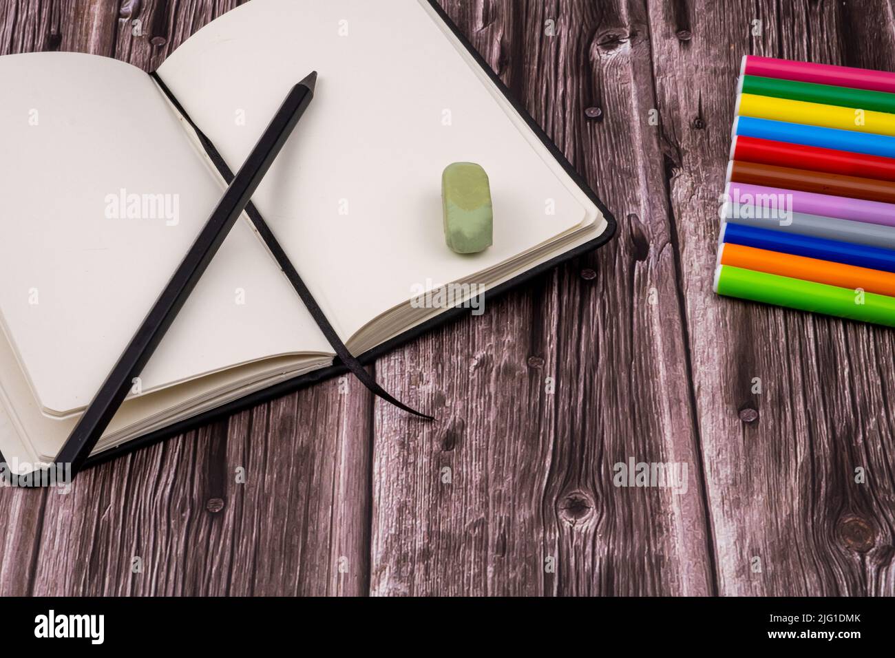 Varie forniture scolastiche come pennarelli, penne colorate e pennarelli, notebook e cancellatore. Sulla parte superiore di un tavolo di legno. Torna a scuola. Foto Stock