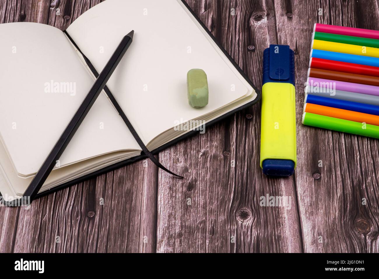 Varie forniture scolastiche come pennarelli, penne colorate e pennarelli, notebook e cancellatore. Sulla parte superiore di un tavolo di legno. Torna a scuola. Foto Stock