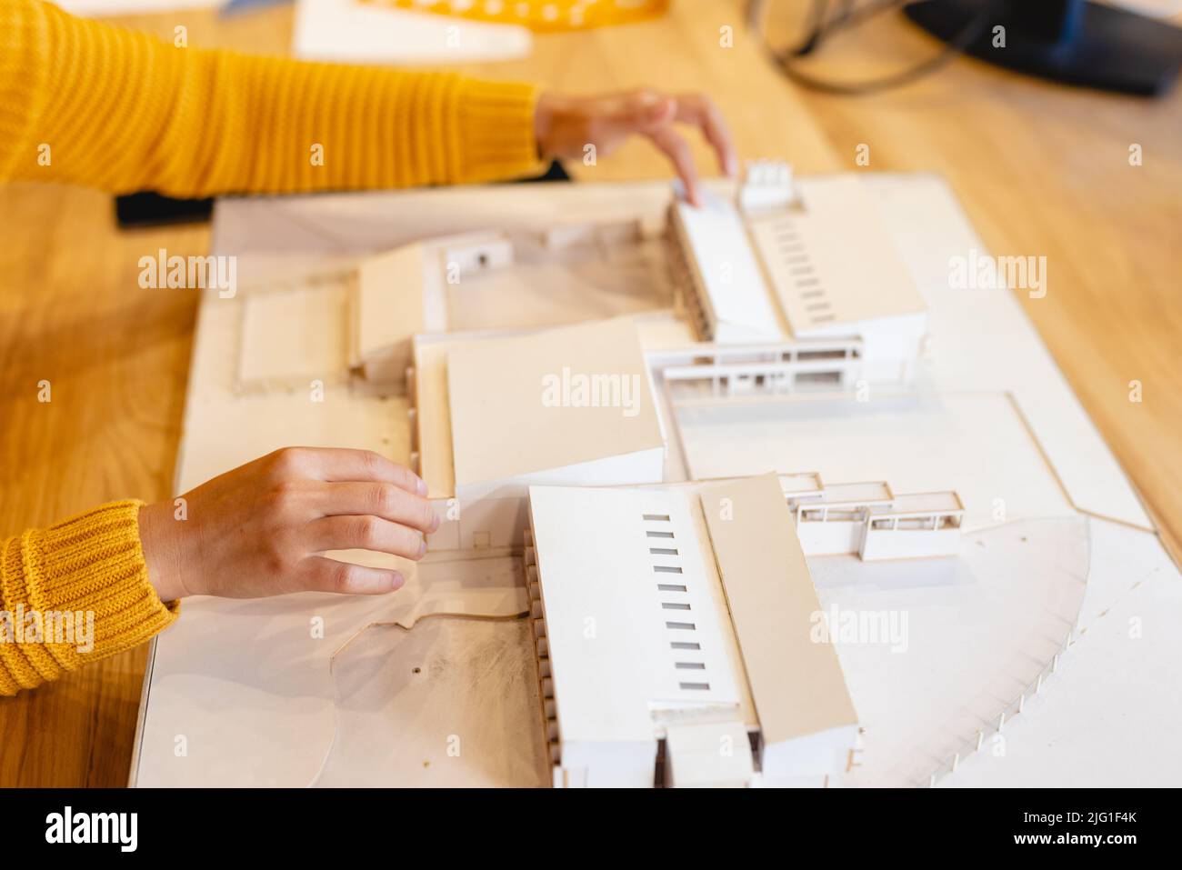 Immagine ritagliata dell'architetto biraciale femminile che fa un modello architettonico in ufficio creativo Foto Stock