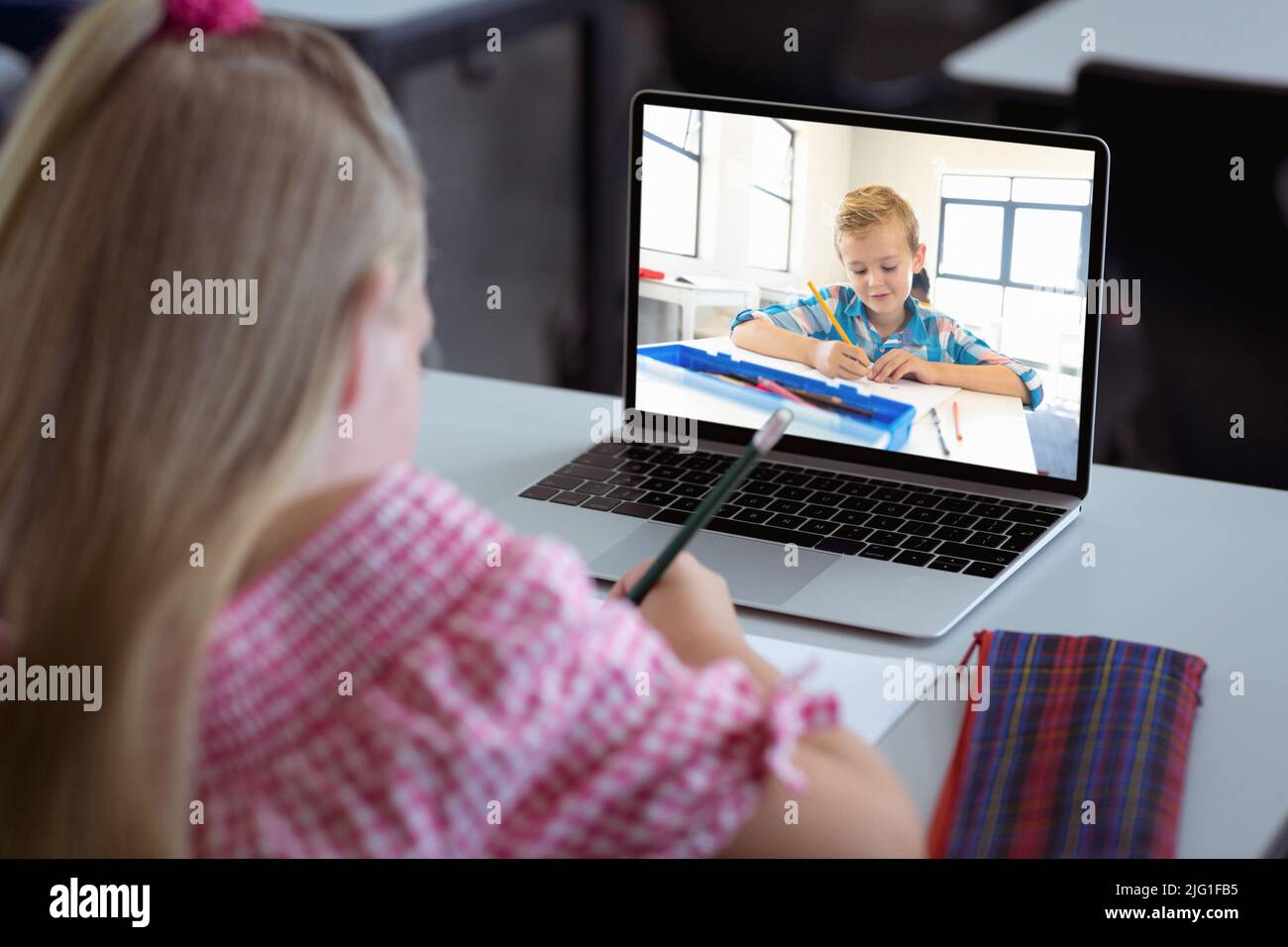 Ragazza caucasica con i capelli biondi scrivere note mentre studiano in classe online sul portatile a casa Foto Stock