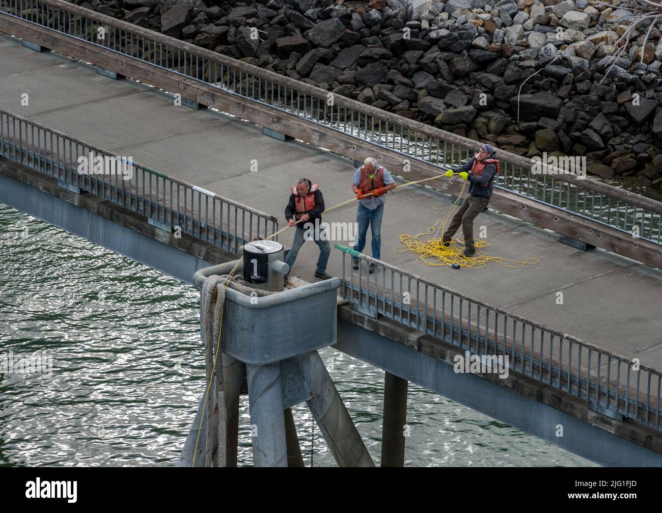 Skagway, AK - 6 giugno 2022: Lavoratori portuali che trasportano le funi pesanti per fissare la nave da crociera al porto Foto Stock