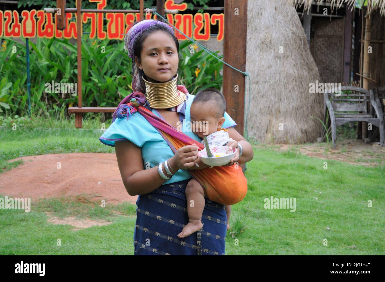 Donna a collo lungo Padaung tribù (Kayan Lahwi), nutrendo il bambino. Pattaya, Tailandia Foto Stock