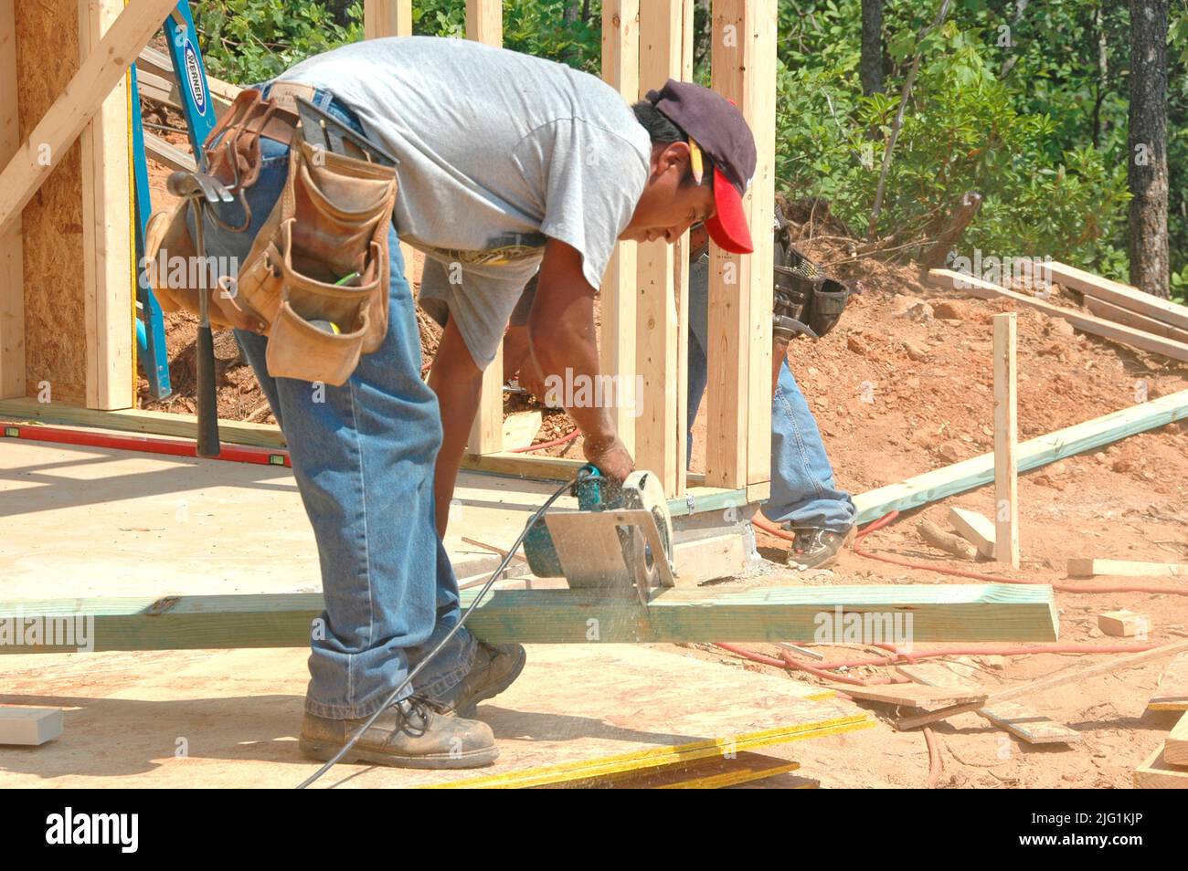 Latin equipaggio di lavoro cuting in unasafe senza la protezione edificio bastone di legno costruita casa misura taglio chiodatura giornata calda Foto Stock