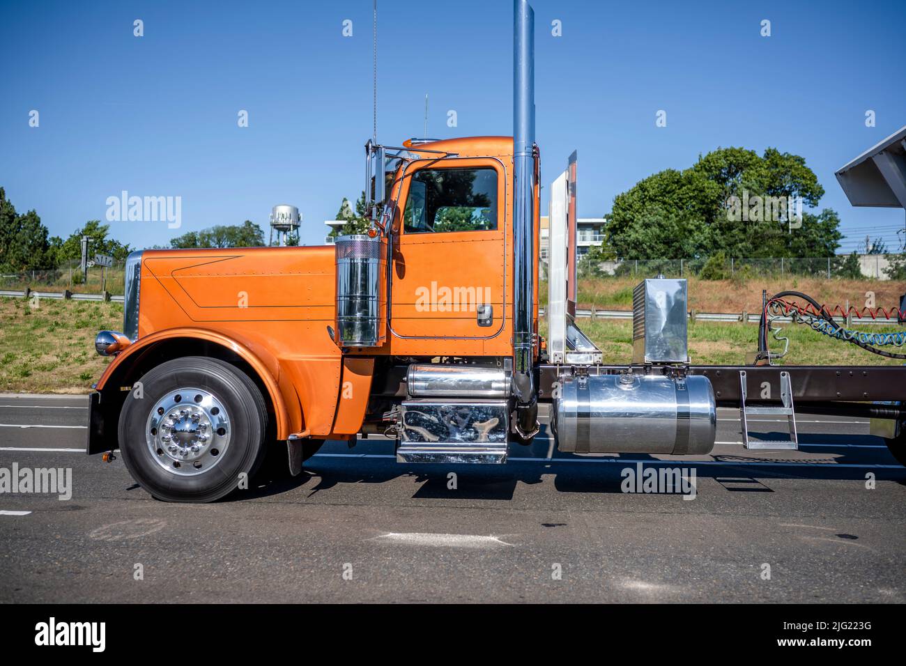 Profilo della cabina basso per migliorare l'aerodinamica trattore semi-camion arancione classico con carro di grandi dimensioni con accessori cromati e tubi di scarico alti per il trasporto del carico i. Foto Stock