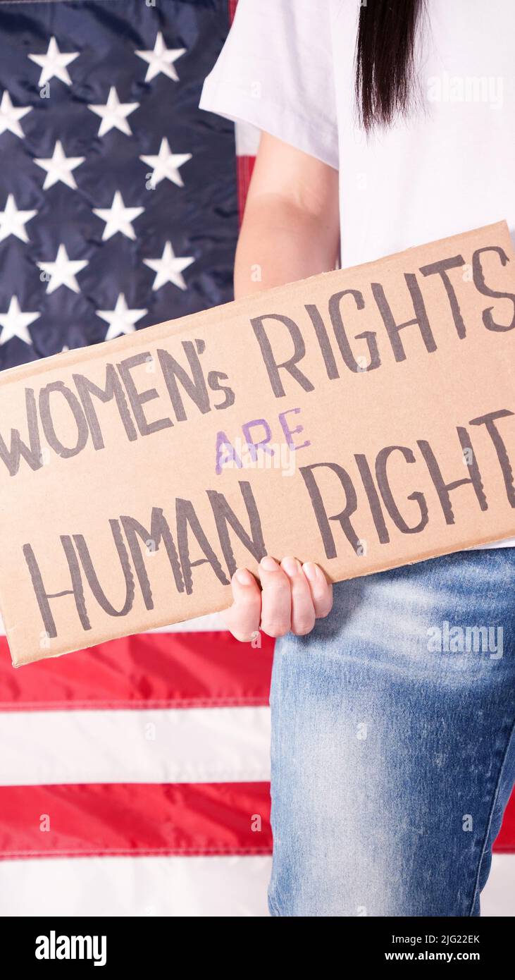 Donna sta tenendo un segno Womens diritti sono diritti umani US bandiera sullo sfondo. Protesta contro la legge anti-aborto. Sciopero femminile. Diritti delle donne libertà Foto Stock