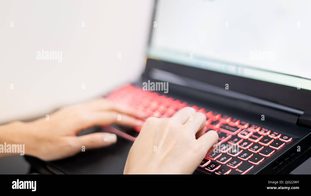 Mano femminile che utilizza il laptop mentre rimane a casa a causa dell'epidemia di Covid, conferenza online, attività di scrittura. Foto Stock