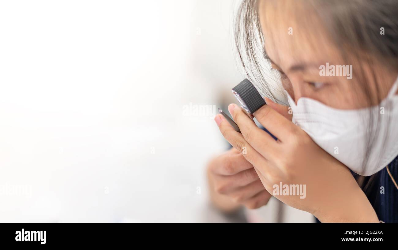 Femmina con loupe e pinzette mentre si esamina la pietra preziosa come la sfaccettatura, incisioni per separare il tipo di pietra preziosa. Foto Stock