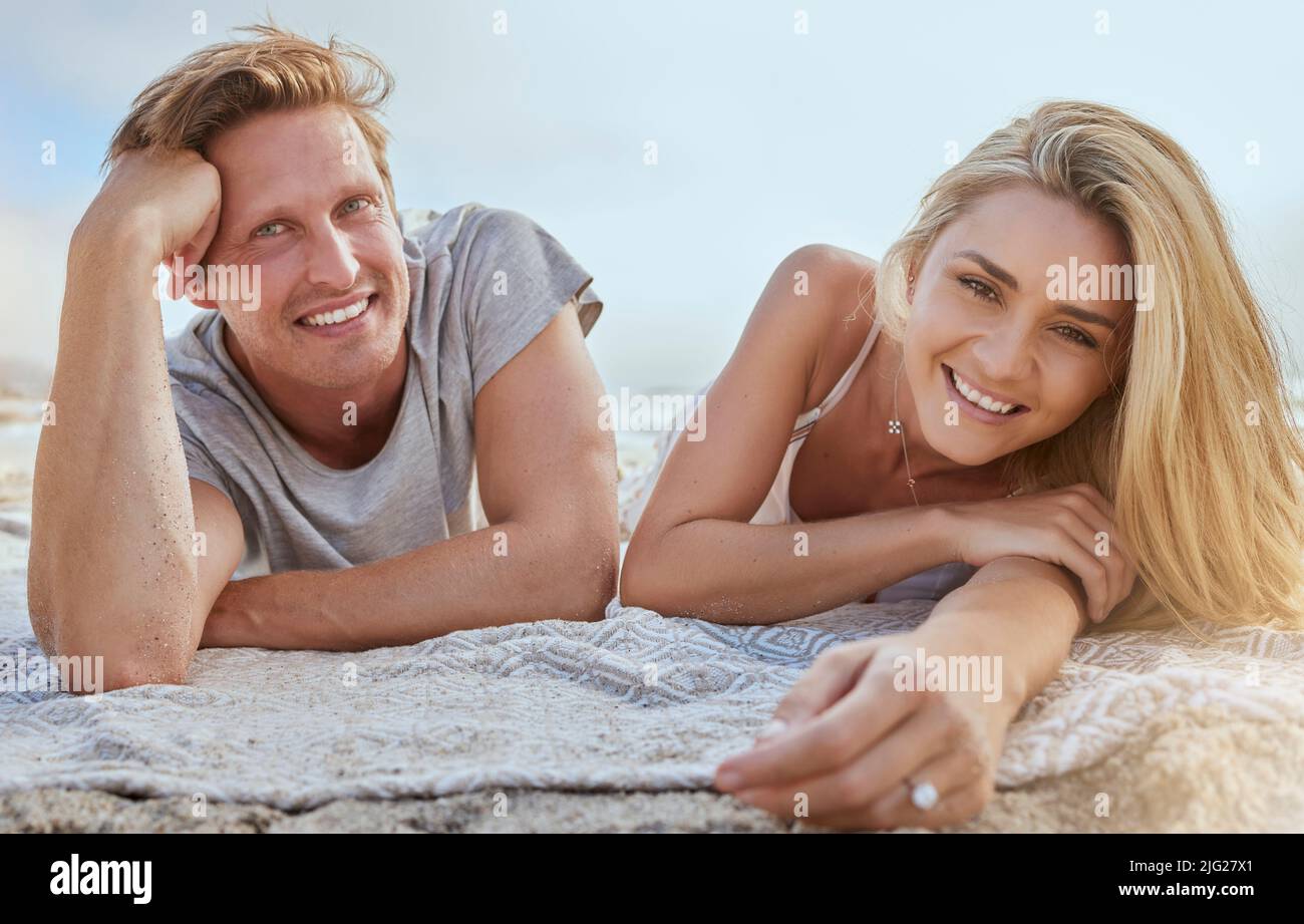 Ritratto di giovane coppia felice sdraiato su coperta e godendo vacanza in spiaggia. Sorridendo giovane biondo uomo e donna rilassandosi sulla riva e godendo loro Foto Stock