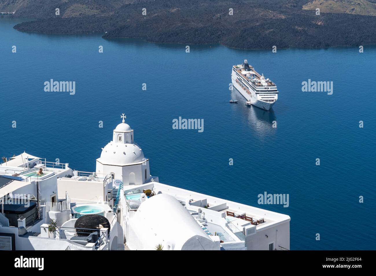 Una nave da crociera vicino all'isola di Santorini, in Grecia. Santorini è un'iconica destinazione turistica del Mar Mediterraneo Foto Stock