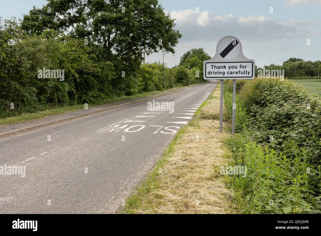 Una corsia di campagna stretta con segnali di limite di velocità nazionali Foto Stock