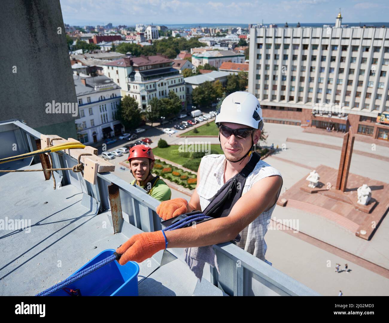 Alpinismo industriale. Pulitori professionali appesi sulle funi mentre puliscono i finestrini del grattacielo. Due uomini lavafinestre utilizzando gli strumenti di pulizia durante il lavaggio della facciata dell'edificio. Foto Stock