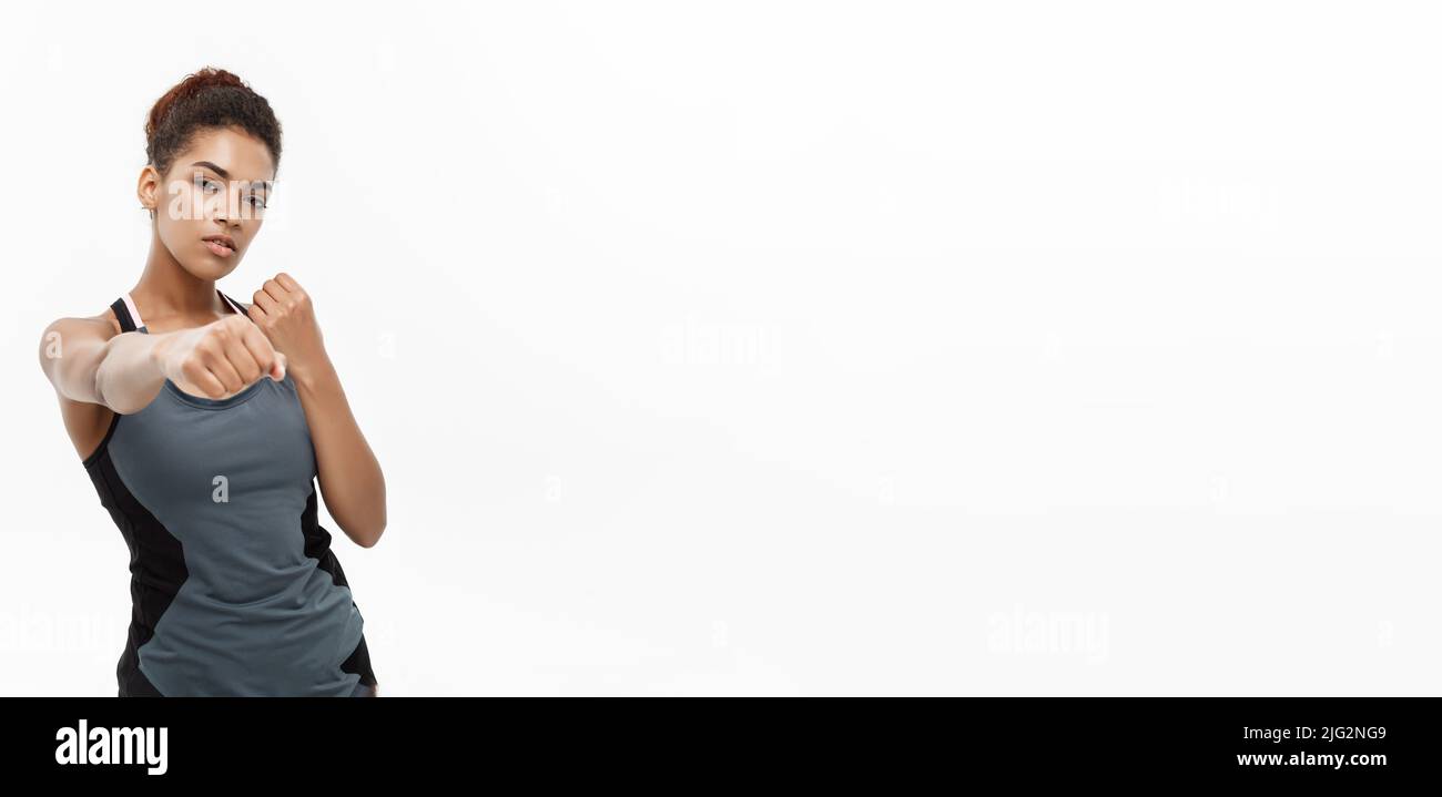 Sana e concetto di Fitness - Ritratto di African American donna punzonatura in aria con volto fiducioso. Isolato su sfondo bianco. Foto Stock