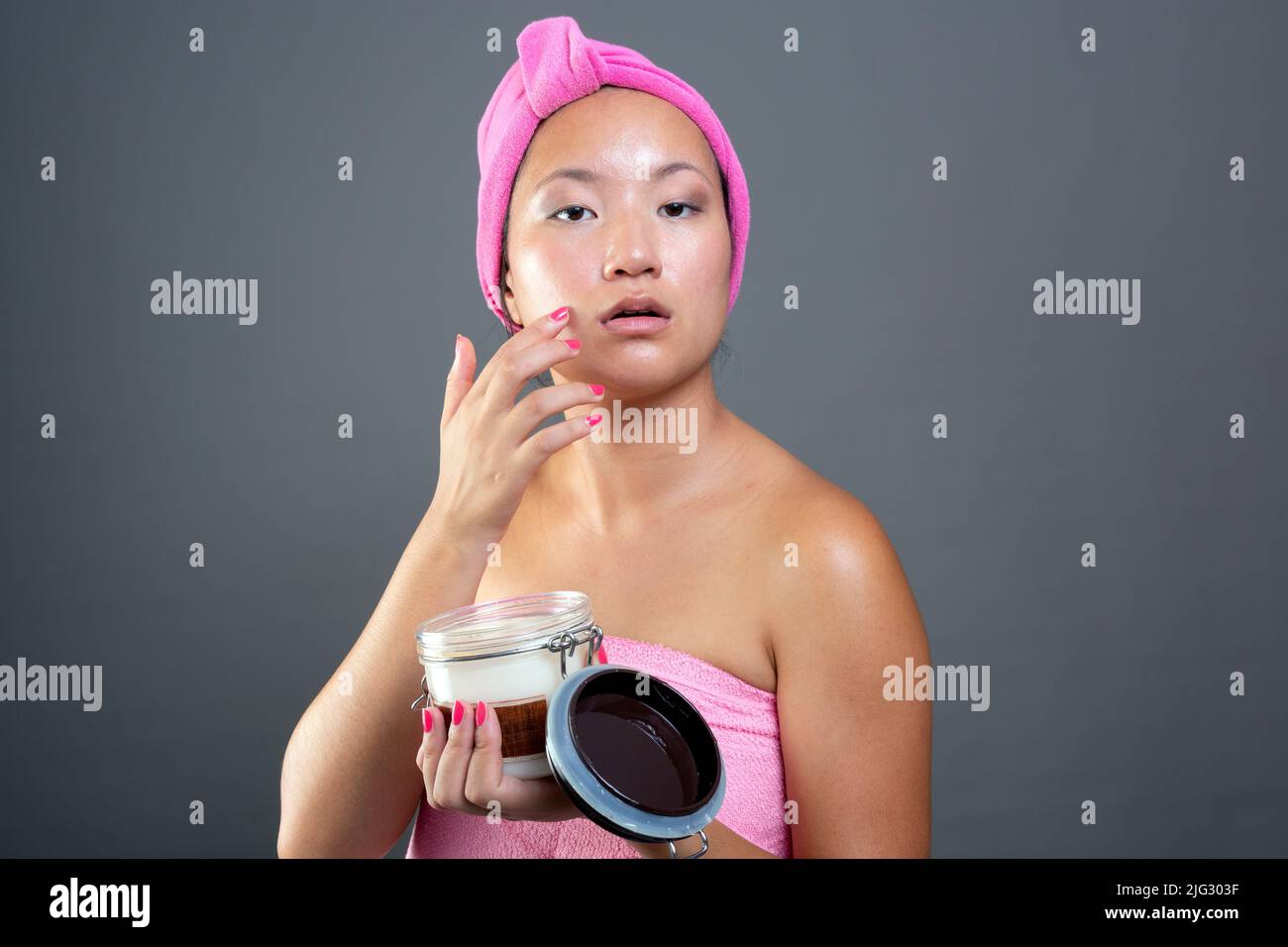 Giovane donna di etnia cinese che si prende cura del suo viso con crema per il viso Foto Stock