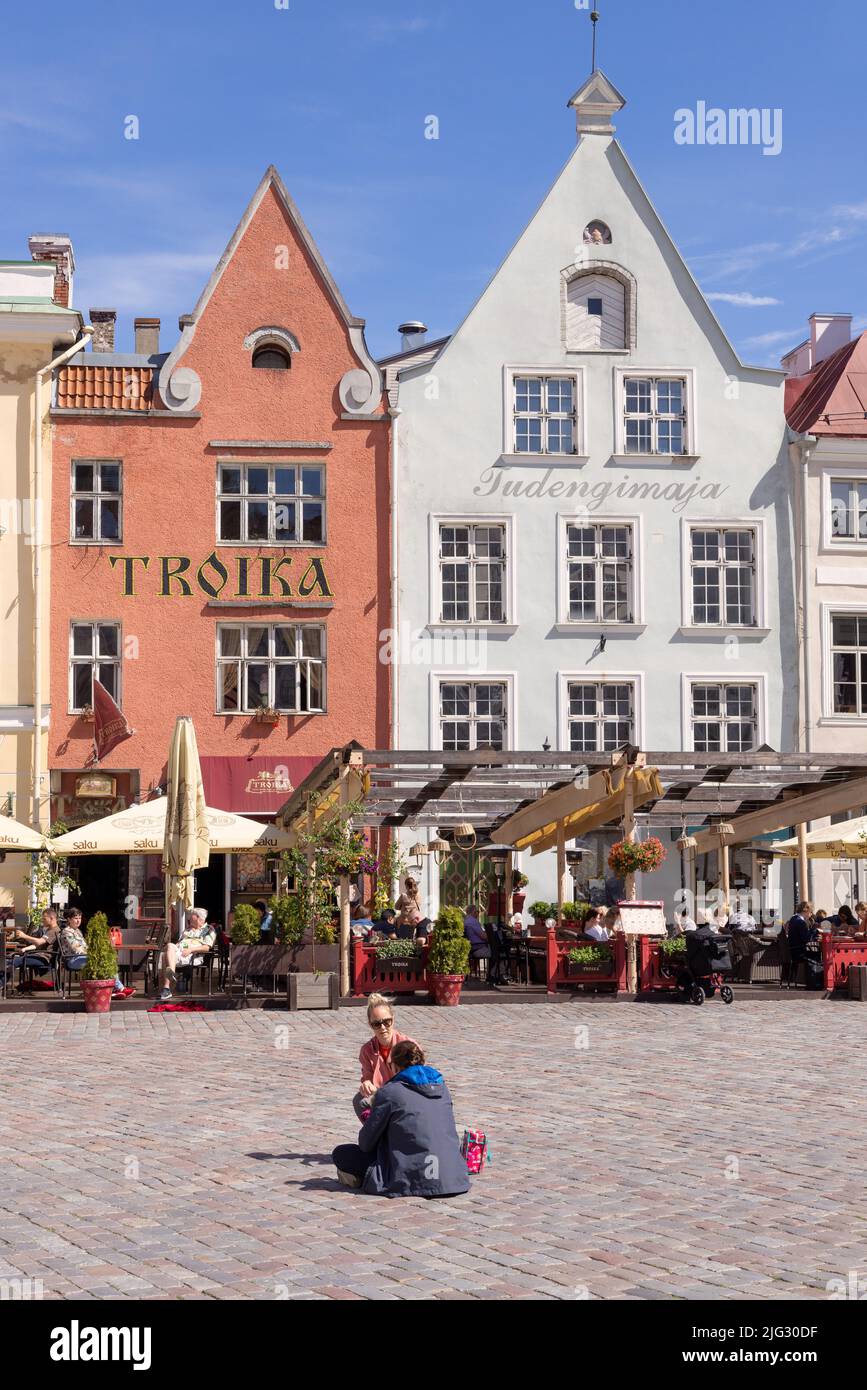 Tallinn turismo; coppia seduta di fronte a edifici medievali Tallinn piazza della città vecchia, ( Tallinn Town Hall Square ) in estate, Tallinn Estonia Europa Foto Stock