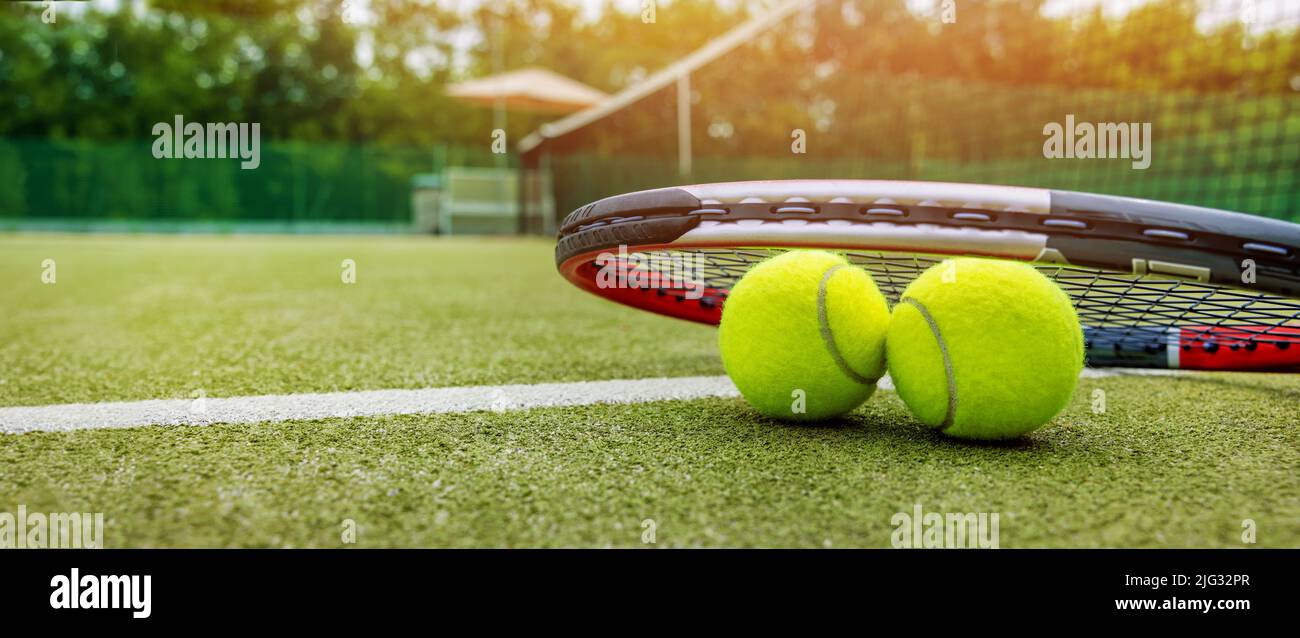 racket da tennis e palle su campo esterno in erba sintetica. banner con spazio copia Foto Stock