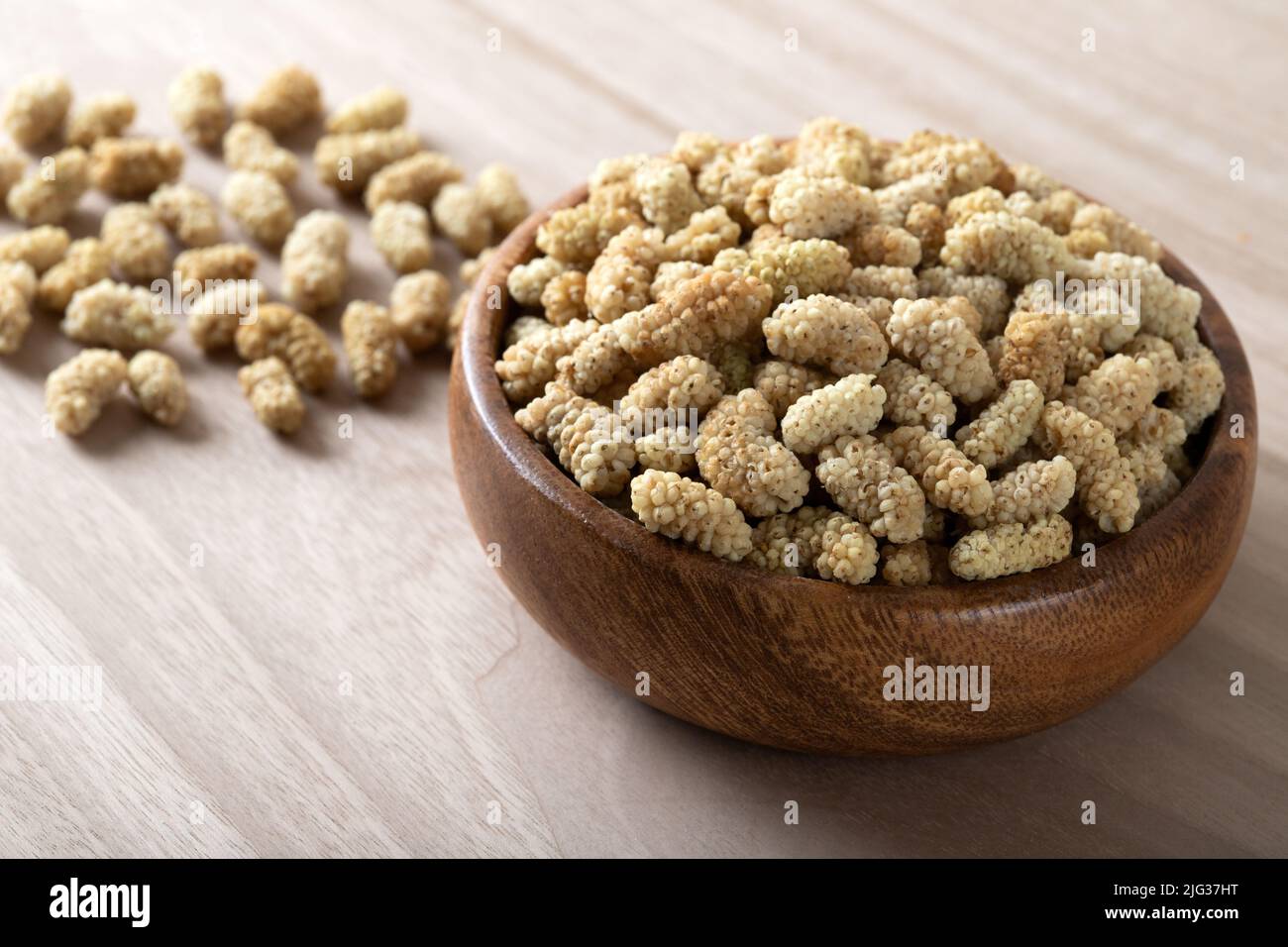 Ciotola piena di gelso secco su sfondo di legno Foto Stock