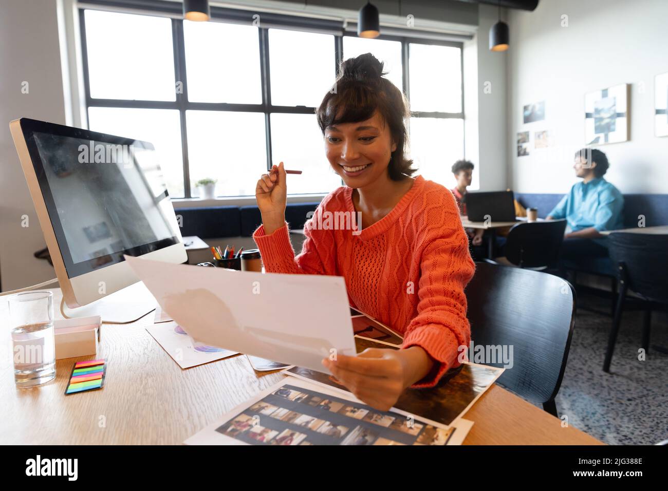 Donna d'affari asiatica sorridente con fotografia al computer desk in ufficio Foto Stock