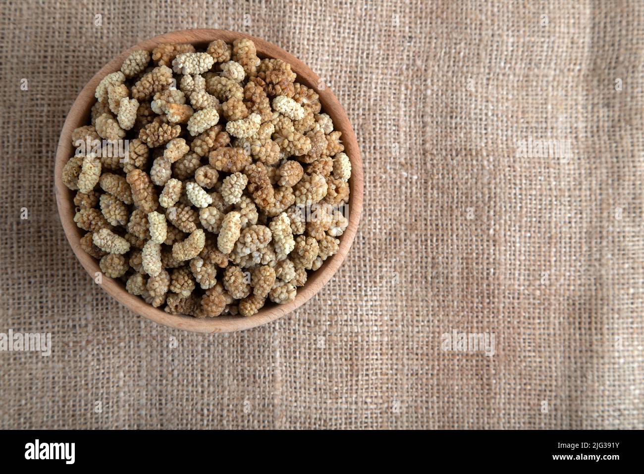 Ciotola piena di gelso secco su un fondo di tessuto Foto Stock