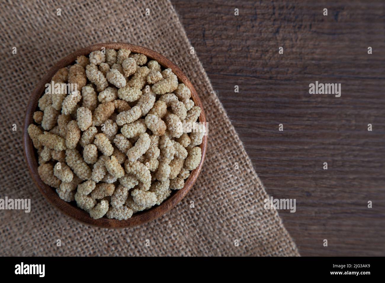Ciotola piena di gelso secco su sfondo di legno Foto Stock