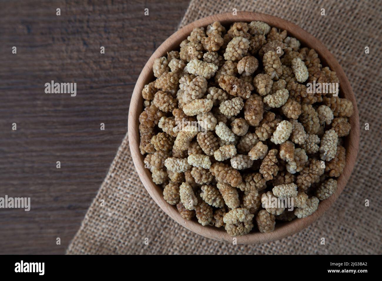 Ciotola piena di gelso secco su sfondo di legno Foto Stock