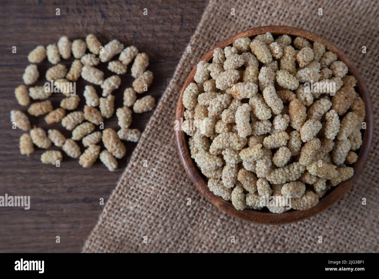Ciotola piena di gelso secco su sfondo di legno Foto Stock