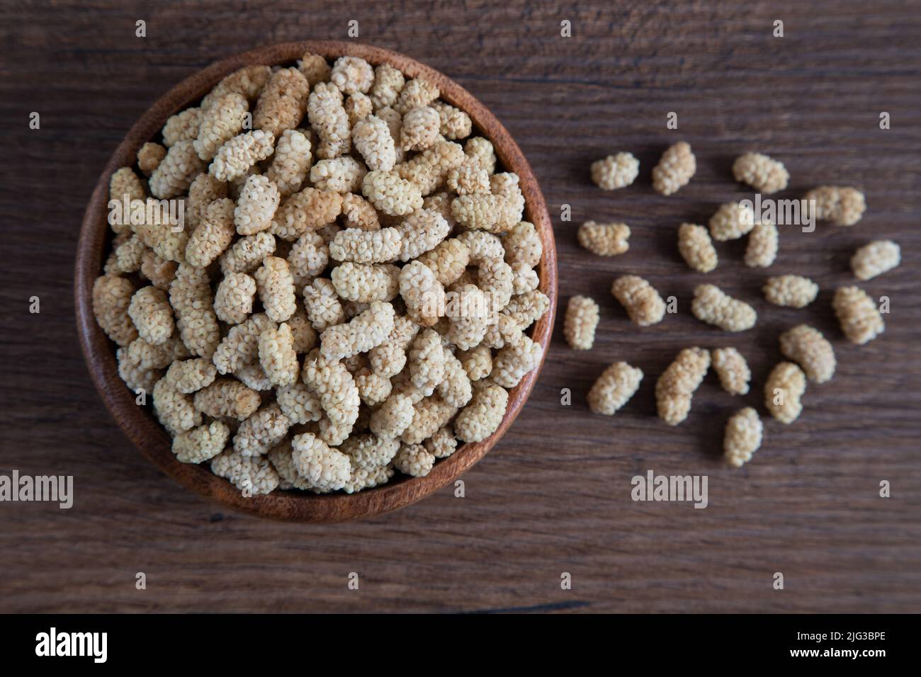 Ciotola piena di gelso secco su sfondo di legno Foto Stock