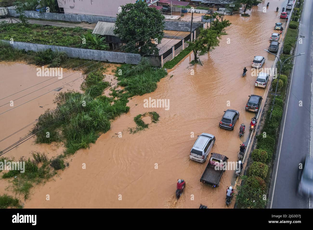 Kendari, Indonesia. 07th luglio 2022. (NOTA EDITORIALE: Immagine scattata con il drone) diversi veicoli sono su una strada allagata a Kendari. Le inondazioni hanno inondato la tangenziale di kendari, causando congestione sulla strada. I veicoli a due e a quattro ruote che vogliono attraversare il percorso alla fine hanno dovuto ridurre la velocità a causa delle inondazioni. (Foto di Andry Denisah/SOPA Images/Sipa USA) Credit: Sipa USA/Alamy Live News Foto Stock