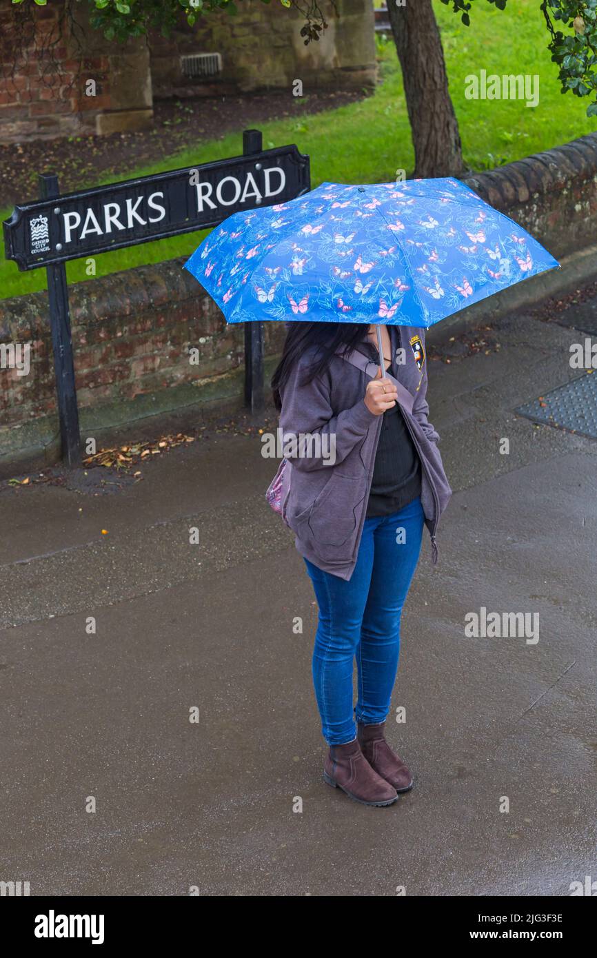 Visitatore con ombrello in piedi nella pioggia battente a Parks Road, Oxford, Oxfordshire Regno Unito in una giornata piovosa bagnata nel mese di agosto Foto Stock