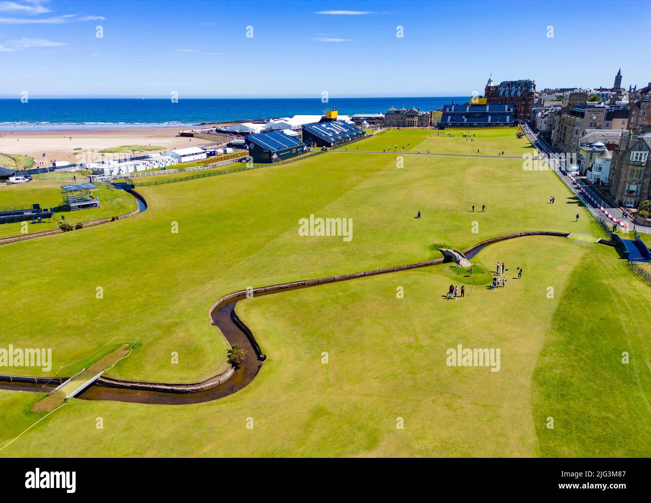 St Andrews, Scozia, Regno Unito. 7 luglio 2022. L'Old Course a St Andrews è un alveare di attività con una settimana per andare fino al primo round del campionato Open 150th. I membri del pubblico sono autorizzati a camminare sui fairway perché il campo Vecchio è un parco pubblico. I turisti hanno ottenuto il massimo da questo accesso per posare per fotografie oltre a famose caratteristiche come il ponte di Burn di Swilken sulla 18th buche. PIC; vista aerea lungo il fairway del 18th attraverso il Burn di Swilken. Iain Masterton/Alamy Live News Foto Stock