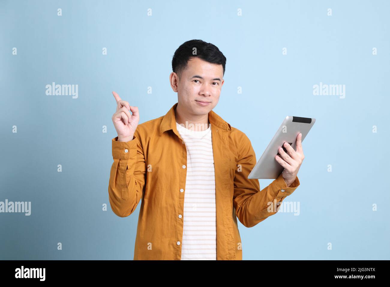 L'uomo asiatico LGBTQ con camicia gialla in piedi su sfondo blu. Foto Stock